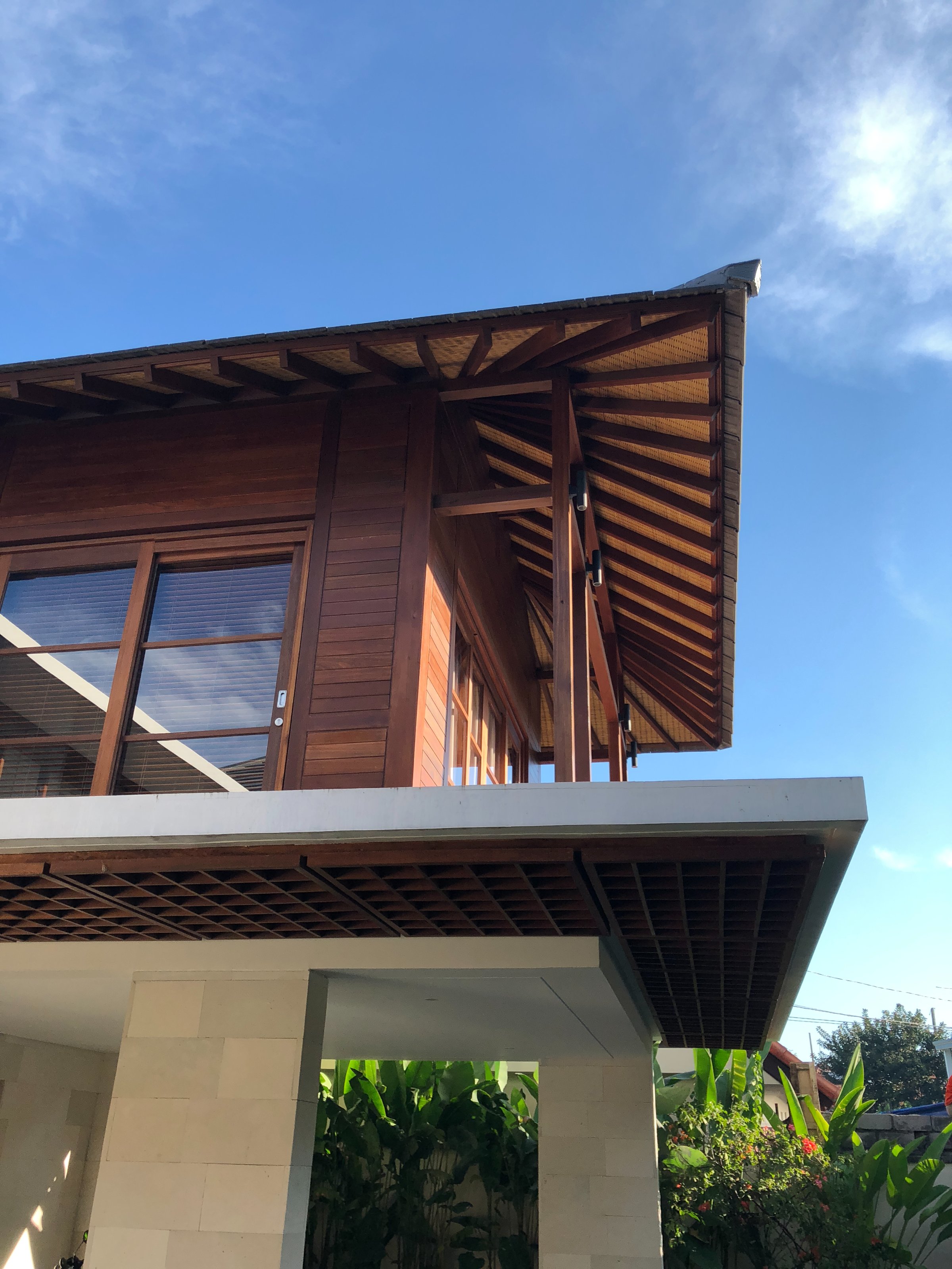 Looking up at exposed wooden roof beams and woven bamboo